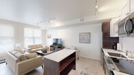 Located at 500 N 3rd St in Bismarck, North Dakota, this one-bedroom, one-bathroom unit offers a well-designed, single-floor layout with a bright, contemporary aesthetic. The open-concept living and kitchen area serves as the heart of the unit, where light wood-tone flooring and crisp white walls create a clean, airy atmosphere. Track lighting runs throughout, providing flexible, modern illumination across the space.

The kitchen is efficiently appointed with rich dark wood lower cabinetry contrasted by white upper cabinets, white subway tile backsplash, light quartz countertops, and a full suite of stainless steel appliances including a refrigerator, range, built-in microwave, and dishwasher. A kitchen island with open shelving below adds both prep space and storage.

The living area benefits from multiple windows dressed with patterned roller shades, filling the room with natural light. A wide entryway hallway features a floor-to-ceiling built-in closet with sleek gold hardware, offering generous storage from the moment you enter.

The bedroom is a comfortable, well-proportioned retreat. The bathroom continues the unit's consistent design language, featuring a dark wood vanity, white countertop, full-width mirror, and a tub-shower combination. Light flooring ties the space together cohesively throughout.