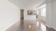 Located at 333 S Glebe Road in Arlington, Virginia, this single-floor residence combines modern updates with a clean, open layout. The spacious living area is defined by richly polished parquet hardwood floors that reflect natural light pouring in through multiple large windows, creating a bright and airy atmosphere. The open-concept design connects the living space to the kitchen, which is outfitted with light wood cabinetry extending to the ceiling for generous storage, stainless steel appliances including a gas range, microwave, and refrigerator, pristine white countertops, and a striking chevron-patterned tile backsplash. A peninsula provides additional counter space and a natural division between the kitchen and living area. The bedrooms continue the hardwood flooring and feature multiple windows that invite natural light and outdoor views. The bathrooms are finished with contemporary taupe subway tile surrounds on the tub-shower combinations, wood-toned vanity cabinetry, and coordinating tile flooring, delivering a cohesive and modern aesthetic. Throughout the residence, the neutral color palette of whites and warm wood tones creates a calm, sophisticated environment well suited to a variety of interior styles.