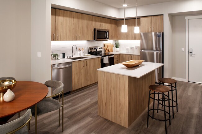 Cocina Design Collection II con gabinetes de roble, encimeras de cuarzo blanco y salpicadero de azulejos blancos - Avalon Alderwood Place