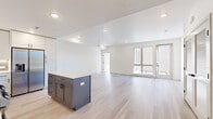 Located at 1070 W Hampden Ave in Englewood, Colorado, this thoughtfully designed 2-bedroom, 2-bathroom residence offers a clean, modern aesthetic throughout its well-appointed single-floor layout. Light wood flooring flows seamlessly across the open-concept living and kitchen areas, creating a bright and cohesive feel. The kitchen is a standout feature, showcasing crisp white shaker cabinetry, a subway tile backsplash, stainless steel appliances, quartz countertops, and a gray center island that doubles as a prep and gathering space. The living area extends naturally from the kitchen, bathed in natural light from large sliding glass doors that open to an outdoor balcony. Both bedrooms are generously proportioned, each featuring ceiling fans, light wood flooring, and large windows that bring in ample daylight and neighborhood views. The primary bedroom includes a dedicated walk-in closet with built-in shelving. The primary bathroom impresses with a floor-to-ceiling tiled glass-enclosed walk-in shower, matte black fixtures, and a white vanity. The second bathroom offers a tiled tub-shower combination with matching matte black hardware and a white vanity. Two closets provide practical storage throughout the home. The overall design is contemporary and clean, emphasizing light, functionality, and modern finishes.
