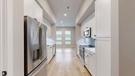 Located at 601 Belpree Dr in Plano, Texas, this efficiently designed single-floor unit offers a thoughtful layout comprising a living room, kitchen, bathroom, and closet. Light-toned luxury vinyl plank flooring flows consistently throughout, creating a cohesive and clean aesthetic.

The galley-style kitchen is a standout feature, lined on both sides with floor-to-ceiling white shaker cabinetry with matte black hardware. Stainless steel appliances — including a French door refrigerator, built-in microwave, and range — are complemented by crisp white countertops and a subtle blue geometric tile backsplash. A single-basin sink with a matte black faucet adds a modern touch.

The living room is bright and open, benefiting from a bank of four windows that fill the space with natural light. A ceiling fan and recessed lighting provide functional illumination throughout.

The bathroom is elegantly appointed with large-format neutral tile flooring, a soaking tub with a full marble-look tile surround, a white vanity with a quartz countertop, and matte black fixtures throughout — delivering a refined, contemporary feel.

The walk-in closet is outfitted with built-in white shelving and hanging storage, maximizing organizational capacity. This unit presents a modern, well-appointed design ideal for efficient and stylish everyday living in Plano, TX.