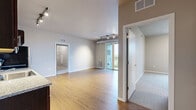 Located at 3029 22nd Ave S in Minneapolis, MN, this 2-bedroom, 2-bathroom residence offers a well-designed single-floor layout that maximizes functionality and comfort. The open-concept living, dining, and kitchen area forms the heart of the home, featuring warm hardwood-style flooring, neutral gray walls, and track lighting that illuminates the space throughout. The kitchen is outfitted with rich dark-espresso cabinetry, granite-style countertops, a full suite of stainless steel appliances including a range, microwave, dishwasher, and refrigerator, and offers a seamless flow into the dining and living areas. Sliding glass doors in the living room open to a private balcony with outdoor views of surrounding greenery, bringing natural light deep into the space. Both bedrooms are carpeted and finished in warm neutral tones; the secondary bedroom features a large window with pleasant tree-lined views. Each bedroom is served by its own bathroom, one featuring a full soaking tub and shower combo with wood-look flooring. Additional highlights include three closets for ample storage, a dedicated laundry area, a utility room, and a hallway connecting all rooms efficiently. The overall ambiance is clean, modern, and move-in ready.