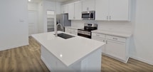 Located at 9002 S Collins St in Arlington, TX, this two-story townhome offers 1,480 square feet of living space across three bedrooms and three bathrooms. The ground floor covers 570 square feet and features an open-plan kitchen and living area, a garage, and an entryway with wood-look vinyl plank flooring and recessed lighting. The kitchen is outfitted with white shaker-style cabinetry, quartz countertops, a tile backsplash, and stainless steel appliances including a side-by-side refrigerator, range, and over-the-range microwave. A dedicated pantry provides additional storage. The upper floor spans 900 square feet and houses all three bedrooms, including a primary suite of 190 square feet with a private bathroom featuring tile flooring, a white vanity with quartz countertop, and an adjoining walk-in closet with built-in shelving. Secondary bedrooms are carpeted and include ceiling fans and closets with natural light from window blinds. A dedicated laundry room on the upper level accommodates a full-size washer and dryer with overhead shelving. The home maintains a consistent neutral color palette and clean, modern aesthetic throughout.