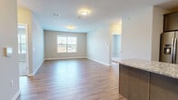 Located at 321 S Broad St in Elizabeth, NJ, this well-appointed residence offers three bedrooms, two bathrooms, and a thoughtfully designed single-floor layout. The open-concept living and dining area immediately impresses with its clean, neutral palette and durable wood-look flooring that flows seamlessly throughout the main living spaces. Natural light filters in through multiple windows, creating a bright and welcoming atmosphere.

The kitchen is a standout feature, showcasing rich dark cabinetry, a granite-topped center island, a classic subway tile backsplash, and a full suite of stainless steel appliances — including a refrigerator with ice maker, gas range, microwave, and dishwasher. The kitchen opens directly to the living area, making it ideal for everyday living and entertaining.

The primary bedroom is a comfortable retreat, complete with a dedicated walk-in closet fitted with wire shelving on both sides. Two additional bedrooms offer plush carpet flooring and windows with exterior views, providing versatile space for guests or a home office. Both bathrooms are cleanly finished, with one featuring tile flooring, a soaking tub with tiled surround, a wood vanity, and a framed mirror. The overall aesthetic throughout is modern, neutral, and move-in ready.