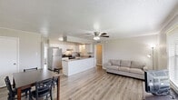 This single-floor, 3-bedroom, 2-bathroom home in Lafayette, Louisiana offers a functional and comfortable layout with consistent light hardwood flooring and neutral tones throughout. The open-concept living area connects seamlessly to the kitchen and dining space, creating a welcoming communal atmosphere. The living room features a ceiling fan with light fixture, crown molding, a textured ceiling, and a large window with blinds that allows natural light to fill the space. The kitchen is well-appointed with white shaker-style cabinetry, granite countertops, stainless steel refrigerator, an electric range, and a built-in peninsula that provides additional prep space and casual seating. An adjacent dining area comfortably accommodates a full dining set. The three bedrooms are bright and neutrally finished, with crown molding and textured ceilings; the primary bedroom includes a ceiling fan, a window with natural light, and generous floor space. The bathrooms are clean and functional, featuring white cabinetry, a large vanity mirror with overhead lighting, and a tub-shower combination with tiled surround. A hallway connects the private areas of the home, and built-in shelving near the kitchen adds convenient storage. The overall aesthetic is clean, modern, and move-in ready.
