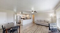 This single-floor, 3-bedroom, 2-bathroom home in Lafayette, Louisiana offers a functional and comfortable layout with consistent light hardwood flooring and neutral tones throughout. The open-concept living area connects seamlessly to the kitchen and dining space, creating a welcoming communal atmosphere. The living room features a ceiling fan with light fixture, crown molding, a textured ceiling, and a large window with blinds that allows natural light to fill the space. The kitchen is well-appointed with white shaker-style cabinetry, granite countertops, stainless steel refrigerator, an electric range, and a built-in peninsula that provides additional prep space and casual seating. An adjacent dining area comfortably accommodates a full dining set. The three bedrooms are bright and neutrally finished, with crown molding and textured ceilings; the primary bedroom includes a ceiling fan, a window with natural light, and generous floor space. The bathrooms are clean and functional, featuring white cabinetry, a large vanity mirror with overhead lighting, and a tub-shower combination with tiled surround. A hallway connects the private areas of the home, and built-in shelving near the kitchen adds convenient storage. The overall aesthetic is clean, modern, and move-in ready.