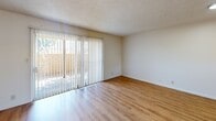 Located at 39900 Blacow Rd in Fremont, California, this two-bedroom, one-bathroom unit offers a well-organized single-floor layout with a clean, neutral aesthetic throughout. Warm hardwood-style flooring extends across all living areas, complementing the crisp white walls and textured ceilings found in most rooms.

The galley-style kitchen is efficiently designed with white cabinetry, light countertops, a stainless steel refrigerator, electric range, over-the-range microwave, and dishwasher. A hallway connects the kitchen seamlessly to the rest of the unit.

The living room is a standout space, featuring large sliding glass doors flanked by vertical blinds that flood the room with natural light and provide direct access to an outdoor patio area. An additional entry door and window offer further views of the surrounding greenery.

Both bedrooms are well-sized with hardwood-style flooring and windows that invite natural light. The primary bedroom includes a mirrored sliding-door closet, while the second bedroom features similarly clean, open walls ideal for flexible use.

The bathroom is bright and functional, featuring a white vanity with storage, a toilet, and a shower-tub combination beneath a window that allows natural light. The hardwood-style flooring carries through here as well, tying the space together cohesively.