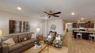 This single-story, 4-bedroom, 2-bathroom home offers a thoughtfully designed layout with generous living space spread across one level. The living room serves as a welcoming centerpiece, featuring wood-look flooring, recessed lighting, a ceiling fan, and large windows that invite natural light. The kitchen is well-appointed with rich dark cabinetry, granite countertops, stainless steel appliances including a French door refrigerator and electric range, and ample storage throughout. Adjacent to the kitchen, the dining area provides a comfortable space for gatherings, with access to natural light through a windowed door. A wide hallway connects the living spaces to the four bedrooms, each finished with the same warm wood-look flooring and neutral tones that create a calm, cohesive atmosphere. The primary bedroom features windows with outdoor views, a ceiling fan, and generous space for a sitting area. The bathrooms are clean and functional, with granite vanity tops and dark cabinetry matching the kitchen aesthetic. One full bathroom includes a tub-shower combo. A dedicated laundry room with a full-size washer and dryer adds everyday convenience. Throughout the home, consistent finishes and a neutral palette create a bright, move-in-ready environment.