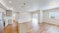 This well-appointed single-floor residence offers two bedrooms and two bathrooms within a thoughtfully designed layout. The open-concept kitchen and living area serves as the heart of the unit, featuring light hardwood-style flooring that runs throughout the main living spaces. The kitchen is equipped with stainless steel appliances, including a refrigerator, range, and microwave, complemented by flat-front cabinetry in a neutral gray-white tone and a white quartz countertop island. Pendant lighting above the island adds a modern touch, while recessed lighting provides consistent illumination. The living area receives natural light through a sliding glass door fitted with vertical blinds, alongside an additional window.

The primary bedroom offers a comfortable footprint with hardwood-style flooring, a window with exterior views, and access to a full en-suite bathroom featuring a double-sink vanity, white quartz countertops, and a tub-shower combination. The second bedroom is carpeted, benefits from natural light, and includes a double-door closet. The second bathroom mirrors the clean, modern aesthetic with subway tile surround and a single-sink vanity. Throughout the unit, a neutral white palette and textured ceilings contribute to a bright, cohesive ambiance.