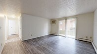 Located at 6458 Cheviot Rd in Cincinnati, Ohio, this one-bedroom, one-bathroom unit offers a well-organized layout across a single floor. The living room is bright and open, featuring wood-style plank flooring, a textured ceiling, a ceiling fan, baseboard heating, and a wall-mounted A/C unit. Sliding glass doors lead directly to a private balcony, allowing natural light to fill the space and providing outdoor views of the surrounding brick building exterior. The kitchen is efficiently designed with white cabinetry, granite-look countertops, a stainless steel sink, and black appliances including a refrigerator, range, and dishwasher — all set on light wood-style flooring. The spacious bedroom continues the wood-style flooring and features a dedicated walk-in closet with built-in wood shelving and a hanging rod, offering generous storage. The full bathroom includes a single-vanity with warm wood cabinetry, a white countertop, and a tiled tub-shower combination. White walls and consistent flooring throughout give the unit a clean, cohesive aesthetic. Baseboard heating is present in multiple rooms, and the overall layout is practical and functional.