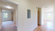 Located at 87 New St in Cambridge, MA, this three-bedroom, one-bathroom residence offers a thoughtfully organized single-floor layout. The interior features a pleasing mix of hardwood flooring and plush carpeting throughout, contributing to a warm and comfortable ambiance.

The kitchen is a functional highlight, equipped with stainless steel appliances including a range, built-in microwave, and refrigerator, complemented by warm maple cabinetry and granite countertops. A peninsula with pendant lighting opens the kitchen toward the living area, enhancing the sense of connectivity. A window over the counter brings in natural light and treetop views.

The spacious primary bedroom is bathed in natural light through a wide bank of windows offering lush green views of the surrounding Cambridge landscape. The two additional bedrooms feature carpeted floors and their own windows with pleasant outdoor views. The hallways, one of which houses the electrical panel, connect the rooms efficiently, with both hardwood and carpeted sections visible throughout.

The full bathroom is clean and well-appointed, featuring a wood-framed vanity with a wide mirror, tile flooring, and a shower-tub combination. Two hallways provide practical circulation throughout the home. Overall, the space presents a bright, functional layout well-suited for comfortable urban living in Cambridge.