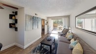 Located in Mesa, Arizona, this single-floor residence offers a thoughtfully designed layout that balances comfort and functionality. The living room serves as the heart of the home, featuring wood-style flooring, a textured ceiling, and a sliding glass door that opens to a private outdoor patio, filling the space with abundant natural light and views of lush greenery. The dining area is positioned adjacent to another set of sliding glass doors, creating a bright and inviting atmosphere ideal for meals and entertaining. The galley-style kitchen is well-equipped with white cabinetry accented by crown molding, stone-toned countertops, a double stainless steel sink, and black appliances including a refrigerator, electric range, microwave, and dishwasher. Wood-style flooring continues throughout, lending a cohesive aesthetic to the space. The bedroom is generously sized with its own sliding glass door providing direct outdoor access, offering both privacy and a seamless indoor-outdoor connection. A second bedroom provides a cozy and well-lit retreat. The bathroom features a wide vanity with a granite-style countertop, white cabinetry, a large mirror with overhead lighting, and a shower-tub combination. Overall, the residence presents a clean, modern, and welcoming ambiance well-suited to the sunny Mesa, AZ lifestyle.
