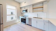 Located at 340 S 500 E in Salt Lake City's vibrant Central East neighborhood, this thoughtfully designed single-floor unit offers a clean, modern aesthetic throughout. Light hardwood flooring runs continuously across every room, tying the space together with a warm, cohesive look.

The open-concept living area is bright and airy, benefiting from large windows and a sliding door that invite abundant natural light and frame views of the surrounding cityscape. A hallway entry features built-in closet storage, providing convenient organization from the moment you step inside.

The contemporary kitchen is well-appointed with sleek gray cabinetry, open wood shelving, a herringbone tile backsplash, stainless steel appliances including a range, microwave, and dishwasher, and a single-basin sink — all designed for both functionality and style.

The unit includes two bathrooms: a primary bath with a backlit vanity mirror, floating vanity, and glass-enclosed walk-in shower, and a secondary bath featuring a full soaking tub and minimalist white finishes. The bedrooms are spacious and bright, with clean white walls, recessed ceiling details, and windows offering views of the neighborhood. The overall ambiance is modern, minimal, and move-in ready.