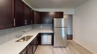 This 2-bedroom, 1-bathroom residence at 125 W Farrell Ave in Ewing, NJ offers a well-organized single-floor layout designed for comfortable everyday living. Rich, dark hardwood floors run throughout the main living areas and bedrooms, adding warmth and a polished aesthetic to the space.

The living area is generously sized, bathed in natural light through large windows fitted with blinds, and equipped with baseboard heating and a wall air conditioning unit for year-round comfort. The neutral gray walls provide a versatile backdrop adaptable to any décor style.

The kitchen is a standout feature, outfitted with dark espresso cabinetry, light quartz-style countertops, a stainless steel refrigerator, a dishwasher, and a sleek tile backsplash. Light-toned flooring in the kitchen contrasts beautifully with the rich cabinetry, creating a modern and functional cooking space.

Both bedrooms are well-proportioned, featuring the same hardwood flooring, neutral walls, and windows that allow natural light to fill each room. Baseboard heating and individual wall AC units are present in the bedrooms as well.

The bathroom offers a clean, classic design with white subway-style tile walls, a distinctive turquoise soaking tub with a shower, a white vanity with ample counter space, and a charming geometric-patterned tile floor.