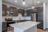 This thoughtfully designed 2-bedroom, 2-bathroom residence is laid out entirely on a single floor, offering a comfortable and functional living environment. The open-concept kitchen and living area serves as the heart of the home, featuring rich dark wood cabinetry, a white subway tile backsplash, stainless steel appliances, recessed lighting, and a generous center island with a clean white countertop illuminated by pendant lights — ideal for both meal prep and casual dining. Light wood-tone flooring flows throughout the main living areas, adding warmth and cohesion to the space.

The primary bedroom is a well-proportioned retreat equipped with a ceiling fan, large windows that invite natural light and outdoor views, and plush carpeting underfoot. The second bedroom also features carpeted floors, a ceiling fan, and a horizontal clerestory window. Each bedroom is paired with its own closet for dedicated storage.

Both bathrooms are finished in a clean, modern style. The primary bath includes dark wood vanity cabinetry, a quartz countertop, a framed mirror, and a glass-enclosed walk-in shower. The second bathroom mirrors this refined aesthetic with a tub-shower combo and light hardwood flooring. Together, these spaces reflect a cohesive, contemporary design throughout.