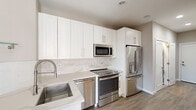 This contemporary apartment offers 660 square feet of efficiently designed living space. The open floor plan maximizes the use of space, creating a seamless flow between the living areas. The kitchen boasts white cabinetry, stainless steel appliances, and a functional layout. Both bedrooms are well-proportioned, with the primary bedroom measuring a spacious 160 square feet. The two bathrooms feature modern fixtures, including glass-enclosed showers and sleek vanities. Large windows in the living areas and bedrooms flood the space with natural light and offer city views. The apartment's neutral color palette, highlighted by light gray walls and warm wood-look flooring, creates a bright and inviting atmosphere. Recessed lighting throughout adds to the modern aesthetic. Sliding closet doors in the bedrooms provide ample storage while maintaining a clean look. This apartment combines style and functionality in a compact urban living space.