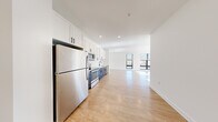 This thoughtfully designed 2-bedroom, 2-bathroom residence offers a clean, modern aesthetic across a single floor. Light-toned hardwood flooring runs throughout, creating a seamless and cohesive feel from room to room. The open-concept layout connects the kitchen directly to the living area, maximizing the sense of space and encouraging easy flow between the two zones. The kitchen is a standout feature, showcasing a two-tone design with crisp white upper cabinetry contrasted by dark navy lower cabinets, all complemented by white countertops, a matte black faucet, and a full suite of stainless steel appliances including a refrigerator, electric range, over-the-range microwave, and dishwasher. Recessed lighting illuminates the kitchen and living area, adding a polished finish. The living room benefits from a large window that invites natural light and outdoor views. Both bedrooms are bright and well-proportioned, with the primary bedroom offering generous dimensions and access to a dedicated closet fitted with wire shelving for organized storage. The bathrooms are finished in a clean, minimalist style with white vanities featuring shaker-style cabinetry and matte black hardware. White walls throughout the residence contribute to a fresh, contemporary ambiance.