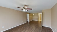 This single-story residence offers two bedrooms and two bathrooms within a thoughtfully organized floor plan. The open living area features rich, dark hardwood-style flooring, warm neutral-toned walls, and a ceiling fan with light kit. A sliding glass door with vertical blinds fills the space with natural light and provides outdoor views, creating a bright and airy atmosphere. An adjacent dining area is defined by a pendant light overhead, adding a subtle decorative touch.

The kitchen is equipped with white cabinetry offering generous storage, granite-style countertops, a double stainless steel sink, a dishwasher, and a white electric range. Light tile flooring keeps the space clean and practical.

Both bedrooms are carpeted and feature ceiling fans, neutral walls, and windows that admit natural light. Each room includes closet space, with the primary bedroom offering a walk-in closet. The two bathrooms are finished with tile flooring, white vanity cabinetry, granite-style countertops, and tub-shower combinations with white tile surrounds, providing a clean and functional design throughout the residence.