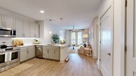 Located at 11023 Moonbug Ct in Charlotte, NC, this well-appointed 2-bedroom, 3-bathroom single-floor home offers a thoughtfully designed layout with modern finishes throughout. Light wood-tone luxury vinyl plank flooring runs continuously through the space, creating a cohesive and clean aesthetic.

The open-concept kitchen and living area form the heart of the home. The kitchen features gray shaker-style cabinetry, a white quartz peninsula with pendant lighting, a stainless steel dishwasher, and a full-size stainless steel refrigerator. The living room flows naturally from the kitchen, with a warm taupe accent wall, ceiling fan, and a large window with sliding glass door access that fills the space with natural light.

The primary bedroom is a serene retreat highlighted by a sage green accent wall, natural light from a large window, a ceiling fan, and a generously sized walk-in closet with built-in shelving and dual hanging rods. The second bedroom maintains the same bright, neutral palette with ample natural light and its own walk-in closet.

The bathrooms are finished with white subway tile tub surrounds, clean white vanities, and LVP flooring. A bright entry area with double closet doors and stainless steel appliances provides practical storage near the front entrance, completing this functional and stylish home.
