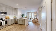 Located at 11023 Moonbug Ct in Charlotte, NC, this well-appointed 2-bedroom, 3-bathroom single-floor home offers a thoughtfully designed layout with modern finishes throughout. Light wood-tone luxury vinyl plank flooring runs continuously through the space, creating a cohesive and clean aesthetic.

The open-concept kitchen and living area form the heart of the home. The kitchen features gray shaker-style cabinetry, a white quartz peninsula with pendant lighting, a stainless steel dishwasher, and a full-size stainless steel refrigerator. The living room flows naturally from the kitchen, with a warm taupe accent wall, ceiling fan, and a large window with sliding glass door access that fills the space with natural light.

The primary bedroom is a serene retreat highlighted by a sage green accent wall, natural light from a large window, a ceiling fan, and a generously sized walk-in closet with built-in shelving and dual hanging rods. The second bedroom maintains the same bright, neutral palette with ample natural light and its own walk-in closet.

The bathrooms are finished with white subway tile tub surrounds, clean white vanities, and LVP flooring. A bright entry area with double closet doors and stainless steel appliances provides practical storage near the front entrance, completing this functional and stylish home.