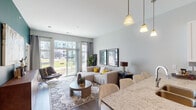 Located at 101 E Fourth St in Newport, Kentucky, this thoughtfully designed single-floor residence offers a seamless blend of modern finishes and comfortable living. The open-concept layout connects the kitchen, dining, and living areas, creating a bright and cohesive space ideal for both everyday living and entertaining.

The kitchen is outfitted with white shaker-style cabinetry, granite countertops, a gray subway tile backsplash, and a full suite of stainless steel appliances, including a French door refrigerator, electric range, and over-the-range microwave. The living area is anchored by large sliding glass doors that flood the room with natural light and open to a private balcony with outdoor views. A bold teal accent wall adds a striking design element that carries through to the bedroom.

The dining area offers an intimate setting with neutral tones and tasteful wall décor. The bedroom features a teal feature wall, plush carpeting, and a window with exterior views, delivering a calm and restful retreat. A walk-through closet with built-in shelving leads directly into the en-suite bathroom, which includes a glass-enclosed walk-in shower with large-format tile, a white vanity with granite countertops, and wood-look flooring throughout.