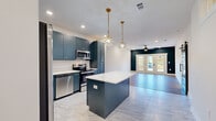 Located at 888 Horizon Boulevard in Athens, GA, this thoughtfully designed single-story residence blends modern aesthetics with functional living. The open-concept layout connects the living area to the kitchen, creating a seamless flow throughout the main living space. Light wood-look flooring runs through the living and bedroom areas, while large-format marble-look tile anchors the kitchen and utility zones.

The kitchen is a standout, featuring bold slate-blue shaker cabinetry, white quartz countertops, a classic subway tile backsplash, and a full suite of stainless steel appliances including a French door refrigerator, range, microwave, and dishwasher. A central island with pendant lighting adds prep space and visual interest.

The living area is anchored by a deep navy accent wall and French doors that invite natural light and provide direct outdoor access. A ceiling fan overhead adds comfort and a modern industrial touch. A stylish black sliding barn door connects areas of the home with a rustic-modern flair.

Bedrooms are bright and well-proportioned, each with wood-look flooring, ceiling fans, and closet space. The bathroom features full white subway tile surrounding a soaking tub with matte black fixtures. Additional highlights include a well-organized pantry with wire shelving and a board-and-batten accent wall in one of the rooms.