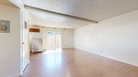 This two-story home offers three bedrooms and two bathrooms thoughtfully distributed across two floors. The main level features an open-concept kitchen and living room with warm wood-look flooring that extends throughout the common areas. The living room is bright and airy, with a large sliding glass door that invites natural light and provides outdoor access. The kitchen is well-appointed with rich wood cabinetry, a decorative tile backsplash, ample counter space, and a window that further enhances the natural light. A bathroom on this level includes tile flooring, a wall-mounted sink with a mirrored medicine cabinet, and convenient access to the main living area. Upstairs, the three carpeted bedrooms offer a comfortable and quiet retreat. Each bedroom features clean white walls and closet storage, with select rooms enjoying natural light from windows. The primary bedroom provides a generous footprint among the three. The second full bathroom features tile flooring, a tub-shower combination, and overhead cabinetry for storage. Throughout the home, textured ceilings and exposed beams add character, while the neutral color palette creates a clean, move-in ready canvas adaptable to a variety of styles.