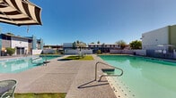 Located at 1737 W Missouri Ave in Phoenix, Arizona, this single-story community property centers around a well-appointed outdoor common area designed for relaxed desert living. The focal point of the space is a pair of generously sized swimming pools with clear, blue-green water, concrete pool surrounds, and built-in entry handrails. The pools are complemented by patches of green turf and landscaped areas that provide a refreshing contrast to the surrounding hardscape.

Scattered throughout the pool deck are shaded seating areas furnished with patio tables, chairs, and large umbrellas, offering comfortable spots to gather under the abundant Phoenix sunshine. Mature palm trees and deciduous trees punctuate the courtyard, adding natural character and shade to the environment.

The surrounding architecture reflects a mid-century Southwestern aesthetic, with low-profile stucco buildings in warm earth tones accented by teal and white geometric facades. A pergola-style gated entry provides a defined passage into the courtyard, adding an architectural detail that enhances the overall layout. Perimeter walls and metal fencing create a sense of enclosure and privacy. The entire complex is designed to embrace the open-air lifestyle characteristic of the Phoenix climate, making the outdoor amenity areas a central and functional component of the property.