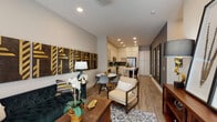 Located at 4015 Aspen Grove Dr in Franklin, TN, this thoughtfully designed single-floor residence offers a seamless blend of modern aesthetics and functional living. The open-concept layout connects the living area, dining space, and kitchen, creating an inviting, cohesive flow throughout the main living zone. The living area is anchored by warm wood-look flooring, recessed lighting, and a striking accent wall featuring bold geometric wood-and-gold wall art that serves as a dramatic focal point. The kitchen is well-equipped with floor-to-ceiling white shaker cabinetry, stainless steel appliances, a dark subway tile backsplash, white countertops, and a portable island that adds versatile prep and casual dining space. A compact dining area with a round table completes the open kitchen zone. The bedroom offers a calming retreat with a deep slate-blue accent wall, natural light from a large window with blinds, and rich wood-look flooring. A second bedroom features a similarly moody gray accent wall with vaulted ceiling lines, adding architectural character. The bathroom is clean and contemporary, showcasing a white vanity with ample cabinetry, a large mirror, chrome hardware, and wood-look tile flooring. Throughout, neutral tones, quality finishes, and stylish details come together to create a refined and comfortable living environment.