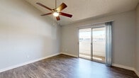 Located at 5220 W Northern Ave in Glendale, Arizona, this single-floor, three-bedroom, two-bathroom residence offers a practical and well-organized layout. The open-concept living, dining, and kitchen area serves as the heart of the home, featuring wood-look plank flooring and a kitchen equipped with warm-toned wooden cabinetry, white countertops, and a stainless steel sink. A built-in shelving unit adjacent to the kitchen provides convenient additional storage. Sliding glass doors lead from the living area directly to a private balcony, allowing natural light to fill the space. The primary bedroom is generously sized, with the same wood-look flooring, a ceiling fan, and direct access to a bathroom and closet. Two additional bedrooms offer plush carpeting, ceiling fans, and windows with blinds for natural light and privacy. The two bathrooms are clean and functional, with one featuring wood-look flooring, a wall-mounted vanity, mirror, and a shower/tub combination. Throughout the unit, textured ceilings and neutral gray walls create a consistent, understated aesthetic. Four closets across the unit ensure ample storage. The layout is efficient and well-connected via a central hallway.