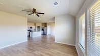 This single-story home is designed with an open-concept floor plan that seamlessly connects the living area and kitchen, creating a spacious and functional layout. Light wood-look flooring runs throughout the main living spaces and bedrooms, providing a cohesive and contemporary aesthetic, while neutral-toned walls contribute to a bright, airy atmosphere.

The kitchen is well-appointed with white shaker-style cabinetry, granite countertops, a subway tile backsplash, and stainless steel appliances including a gas range, built-in microwave, and French door refrigerator. A central island with a granite surface and sink adds prep space and casual dining potential. A dedicated pantry provides additional storage.

The open living area features a ceiling fan with light fixture and flows naturally into the kitchen, making it well-suited for everyday living and entertaining. Bedrooms are accessible via a hallway and include ceiling fans, wood-look flooring, and windows that allow natural light. The bathroom includes a vanity with granite countertop, a mirror, and tile flooring. An attached garage completes the home, offering convenient enclosed parking and storage space.