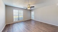 Located in Saint Petersburg, FL, this two-bedroom, one-bathroom unit offers a functional single-floor layout designed for efficient everyday living. The open living room is bright and welcoming, featuring wood-style laminate flooring, a textured ceiling, a ceiling fan with light fixture, and large windows that invite generous natural light. A glass-panel door provides additional brightness and connects the space to the outside. The kitchen flows directly from the living area via a pass-through counter, and is equipped with white cabinetry, dark granite-style countertops, black appliances including a refrigerator and electric range, and durable wood-style flooring that continues from the main living space. Both bedrooms are carpeted for comfort, with neutral tones and ceiling-mounted ventilation. The primary bedroom includes a ceiling fan and a window overlooking outdoor greenery, enhancing the sense of space and airflow. A dedicated closet provides additional storage. The bathroom features a full tub-shower combo with white tile surround, chrome fixtures, and matching wood-style flooring. Throughout the unit, a consistent neutral color palette and clean finishes create a cohesive, move-in-ready atmosphere.