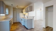 This single-floor residence at 409 Riverhill Loop in Laredo, Texas, offers a clean, functional layout designed for comfortable everyday living. Throughout the unit, warm wood-look flooring creates a cohesive and inviting aesthetic, complemented by crisp white walls and consistent ceiling fans that provide both light and air circulation.

The living area is open and airy, with a ceiling fan overhead and a pass-through window connecting to the kitchen, promoting a sense of connectivity between the spaces. Natural light filters in through blinded windows, keeping the interior bright and welcoming.

The kitchen is well-appointed with gray shaker-style cabinetry, light marbled countertops, and a full suite of white appliances including a refrigerator, electric range, and dishwasher. A peninsula counter provides additional workspace and a natural divide between the kitchen and living areas. A dedicated pantry or utility closet adds to the kitchen's practicality.

The bedrooms are comfortably sized, each with wood-look flooring, windows with blinds for privacy, and ample wall space. Two full bathrooms serve the unit, each featuring a shower-tub combination, white vanity with sink, and matching wood-look flooring, maintaining a clean and uniform finish throughout the home.