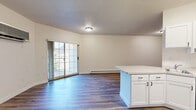 Located at 200 8th Street South in Fargo, North Dakota, this single-floor unit offers a thoughtfully designed layout that makes efficient use of its space. The open-plan kitchen and living area serves as the heart of the unit, featuring durable wood-look plank flooring that flows seamlessly throughout. The kitchen is outfitted with crisp white shaker-style cabinetry, light countertops, a stainless steel dishwasher, range, and refrigerator, providing a clean and functional cooking environment. A peninsula adds additional counter space and enhances the open feel between the kitchen and living areas. The living room benefits from a wall-mounted mini-split HVAC unit and a baseboard heating system, ensuring year-round comfort. A sliding glass door floods the space with natural light and provides access to an outdoor area. The bathroom is finished with the same wood-look flooring, a white vanity with under-mount sink, ample cabinetry, and towel bars, maintaining the clean aesthetic found throughout the unit. A dedicated utility room adds practical storage and functionality. Neutral wall tones and textured ceilings complete the understated, move-in-ready interior of this Fargo residence.