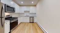 Located at 15 Douglas Terrace in North Providence, Rhode Island, this single-floor unit offers a well-designed layout with clean, contemporary finishes throughout. Light-toned hardwood flooring runs consistently across the living areas and bedrooms, contributing to a bright and cohesive aesthetic.

The kitchen is a standout feature, outfitted with white shaker-style cabinetry, granite countertops, a subway tile backsplash, and a full suite of stainless steel appliances including a gas range, over-the-range microwave, dishwasher, and refrigerator. Recessed lighting illuminates the space efficiently.

The living areas are generously proportioned, with natural light entering through multiple windows that offer views of surrounding greenery. Baseboard heating is present throughout, and select rooms include wall-mounted air conditioning units. One bedroom features a spacious walk-in closet with a sliding door and dedicated rod storage.

The bathroom is thoughtfully appointed with large-format tile flooring, a frameless sliding glass shower enclosure with white subway tile surround, a granite-topped vanity, and brushed nickel fixtures. The overall palette of warm whites and neutral tones creates a calm, move-in-ready environment throughout the unit.