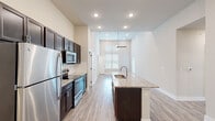 This single-story residence in Hammond, Louisiana offers a thoughtfully designed layout across three bedrooms and two full bathrooms. The open-concept kitchen serves as a central feature, showcasing soaring ceilings, dark espresso cabinetry extending to impressive heights, a white subway tile backsplash, and stainless steel appliances including a refrigerator, range, and built-in microwave. A granite-topped island with an integrated sink anchors the kitchen, providing additional prep space and a natural gathering point that flows into the living area. Light wood-tone luxury vinyl plank flooring runs consistently throughout the unit, lending a clean, cohesive aesthetic.

Each bedroom is well-proportioned, featuring neutral warm-toned walls, blinds-covered windows that admit natural light, and ceiling fans for climate comfort. The bedrooms offer access to closets for storage needs. Both bathrooms include granite-topped dark vanities and tub-shower combinations, with one bathroom featuring a built-in shelving unit. A dedicated laundry room houses a full-size washer and dryer alongside upper cabinetry for additional storage. Overall, the unit presents a modern, move-in-ready interior with consistent finishes throughout.