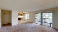 Located at 125 Greenbank Rd in Wilmington, Delaware, this single-floor, two-bedroom, one-bathroom residence offers a practical and comfortable layout. The open living room is carpeted and filled with natural light, featuring a sliding glass door that leads directly to a private balcony overlooking greenery. A ceiling fan is centrally positioned between the living and kitchen areas, enhancing airflow throughout the shared space. The kitchen is efficiently designed in an L-shape configuration, equipped with dark wood cabinetry topped with lighter upper cabinets, laminate countertops, white appliances including a refrigerator, electric range, and dishwasher, and a tiled backsplash. Durable tile flooring completes the kitchen area. Both bedrooms are carpeted and feature neutral walls with natural light from windows. The generously sized primary bedroom includes dedicated closet space, and the second bedroom is equally well-appointed with its own closet. The bathroom features light blue tile wainscoting, wood-look flooring, a vanity with mirror cabinet, and a combined tub and shower. With five closets distributed throughout, storage is plentiful. A utility room and a hallway round out this well-organized floor plan.