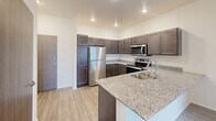 This single-floor residence at 4209 Brett Ave in Sioux Falls, South Dakota, offers a thoughtfully designed layout with contemporary finishes throughout. The kitchen serves as a focal point of the home, showcasing rich dark-stained cabinetry extending to the ceiling, speckled granite countertops, a stainless steel sink, and a full suite of stainless steel appliances including a refrigerator, electric range, microwave, and dishwasher. Light wood-look flooring runs through the main living and kitchen areas, contributing to a clean, cohesive aesthetic. Recessed lighting illuminates both spaces effectively.

The living area provides access to a private balcony through sliding glass doors, allowing natural light to fill the room and offering views of the surrounding neighborhood. Carpeted bedrooms provide a softer, quieter environment, with windows fitted with blinds for privacy and natural light control.

Two bathrooms serve the home: one features a walk-in shower with tile-look flooring and granite vanity, while the second includes a full soaking tub with a curved shower rod and matching finishes. A dedicated laundry area houses a full-size washer and water heater, adding practical convenience to the overall layout.