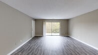 Located at 3450 Evans Road in Atlanta, GA, this single-floor, 2-bedroom, 2-bathroom residence offers a practical and comfortable layout with modern finishes throughout. The open living room is a welcoming centerpiece, featuring durable wood-look plank flooring, neutral taupe walls, and a textured ceiling. A sliding glass door floods the space with natural light and opens to a private balcony overlooking a serene, tree-lined backdrop. The kitchen is well-equipped with white shaker cabinetry, a classic subway tile backsplash, white quartz-style countertops, stainless steel appliances including a dishwasher and refrigerator, and an electric range. Both bedrooms are carpeted for comfort and include dedicated closets, providing ample storage. The primary bedroom is generously sized with its own en-suite bathroom featuring a tiled walk-in shower. The second bathroom includes a full tub-shower combination with white tile surround and a granite-topped vanity. A hallway connects the private quarters, and the layout flows efficiently throughout. The consistent neutral color palette and clean finishes create a cohesive, move-in-ready ambiance across the entire space.