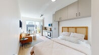 Located in the heart of Portland's vibrant Pearl District at 1925 NW Overton St, this efficiently designed studio offers a thoughtfully organized single-floor layout that maximizes every inch of space. The open-plan main area seamlessly integrates the living, sleeping, and dining zones, unified by light wood flooring and crisp white walls that create a bright, airy atmosphere throughout.

The kitchen is a standout feature, outfitted with stainless steel appliances including a range, dishwasher, and over-the-range microwave. White upper cabinetry pairs with warm taupe lower cabinets and a subway tile backsplash, all anchored by clean white countertops. Tall floor-to-ceiling cabinetry flanking the sleeping area provides generous built-in storage. A large sliding glass door floods the space with natural light and opens to a private balcony with views of the surrounding Portland streetscape.

The bathroom is finished in a clean, modern style with white walls, light wood-style flooring, matte black fixtures and hardware, and a shower with a curtain enclosure. A hallway connects the main living area to the bathroom, adding a sense of defined separation within the open floor plan. The overall design aesthetic is minimalist and contemporary, making this a functional and stylish urban retreat.