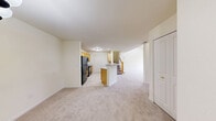 Located at 1260 Club Cir in Brookfield, Wisconsin, this two-story home offers three bedrooms and three bathrooms across a generously proportioned floor plan. The main level commands the majority of the living space and centers around a dramatic living room with soaring vaulted ceilings, a tile-surround fireplace, and sliding glass doors that open to a private balcony overlooking the lush, tree-lined community grounds and a scenic fountain. The kitchen features light maple cabinetry, black appliances including a Whirlpool refrigerator and range, neutral countertops, and tile flooring. A convenient in-unit stacked washer and dryer is tucked just off the kitchen. The bathrooms are finished in light tile with white vanities; one includes a soaking tub and lighted mirror, while another offers a glass-door shower. The bedrooms are carpeted in neutral tones and filled with natural light through slatted blinds. The spacious primary bedroom includes direct balcony access via sliding doors and a private wooded view. The upper level provides additional flexible living space with plush carpet and an open staircase with a classic wood banister, completing this well-designed and comfortable home.