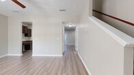 Located at 2174 Rivendell Trace in Nashville, TN, this two-story home offers three bedrooms and three bathrooms across two well-proportioned floors. The main level features a bright, open living room with light hardwood-style flooring, a ceiling fan, and natural light streaming through large windows. The kitchen is well-appointed with rich dark cabinetry, granite countertops, black appliances, recessed lighting, and a central island with a breakfast bar. A convenient half bathroom on the main level features a pedestal sink and wood-style flooring tucked neatly beneath the staircase. A hallway with hardwood-style floors connects the main living areas, with a staircase accented by a warm wood handrail leading to the upper level. The upper floor hosts all three bedrooms, including a generously sized primary suite. The bedrooms feature soft wall-to-wall carpeting and windows with blinds that allow for natural light. Two full bathrooms on the upper level are finished with dark wood vanities, granite-topped counters, and hardwood-style tile floors. A built-in desk area with granite countertops and dark cabinetry provides a functional workspace. Textured ceilings and neutral tones throughout give the home a clean, cohesive aesthetic.