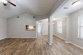Located at 1920 Gunbarrel Rd in Chattanooga, Tennessee, this single-floor home offers a thoughtfully designed layout with a blend of comfort and functionality. The main living area immediately impresses with soaring vaulted ceilings and a textured ceiling finish, creating an open, airy atmosphere. Wood-look plank flooring runs throughout the main living spaces, adding warmth and durability, while a ceiling fan provides year-round comfort. A standout fireplace with a white mantel and tile surround anchors one end of the living area, adding character and a cozy focal point. The galley-style kitchen is well-appointed with white cabinetry, granite-look countertops, black appliances including a gas range and over-the-range microwave, and a stainless steel refrigerator. A pass-through window connects the kitchen to the living area, and a walk-in pantry provides ample storage. Bedrooms are carpeted and generously sized, each featuring ceiling fans and closet space. The bathrooms are clean and functional, offering vanities with granite-look countertops, dark cabinetry, and tub-shower combinations. Natural light filters throughout via blinds-equipped windows, and neutral gray walls provide a versatile backdrop throughout the entire home.