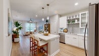 Located on International Drive in Orlando, Florida, this well-designed one-bedroom, one-bathroom residence offers a thoughtfully laid-out open floor plan with clean, modern finishes throughout. Light wood-style flooring flows continuously across the entire space, creating a cohesive and airy atmosphere.

The kitchen is a standout feature, showcasing crisp white cabinetry, open shelving, a classic gray subway tile backsplash, and a full suite of stainless steel appliances including a refrigerator, range, microwave, and dishwasher. A central island with quartz countertops and bar seating connects seamlessly to the combined living and dining area, making it ideal for both daily living and entertaining.

The living room is bathed in natural light from large windows dressed with sheer curtains, and is complemented by a ceiling fan overhead. The space opens to a hallway lined with two closets, providing ample storage.

The bedroom is a comfortable, well-proportioned retreat featuring a window with natural light, a ceiling fan, and direct access to the adjacent living area. Two closets serve the unit conveniently.

The bathroom is finished in a clean, neutral palette with a white vanity, wood-style flooring, open shelving, and a tub-shower combination with tile surround. The overall ambiance of the residence is bright, modern, and move-in ready.