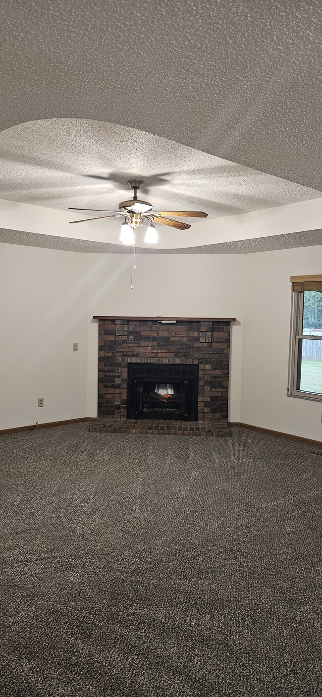 New carpet in living room with fireplace and ceiling fan - 117 Grand Prairie Dr