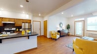 Located at 16609 East Desmont Court in Spokane Valley, WA, this single-floor unit offers a thoughtfully designed open-concept layout that seamlessly connects the kitchen, dining, and living areas. The kitchen is a standout feature, showcasing warm wood cabinetry, dark countertops, a spacious peninsula with pendant lighting overhead, stainless steel appliances including a refrigerator and range, and a double-basin sink — all set atop durable wood-style flooring that extends throughout the main living areas. The living room is bright and welcoming, with large windows that allow ample natural light to fill the space, complemented by a private entry door. A dedicated entryway area provides additional storage and a convenient transition into the home. The bedroom offers plush carpeting, a generously sized closet with sliding wood doors, and a window that brings in natural light, creating a calm and restful retreat. The bathroom is well-equipped with a wide vanity featuring wood cabinetry, a large mirror, and a full tub-shower combination. An in-unit laundry area adds everyday convenience. Throughout the space, recessed lighting and clean white walls contribute to a bright, modern ambiance.