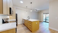 Located at 105 Laurel Hill Rd in Brookfield, CT, this thoughtfully designed one-bedroom, one-bathroom residence offers a clean, modern aesthetic across its single floor. The open-concept living and kitchen area serves as the heart of the home, anchored by a sleek center island with a crisp white quartz countertop, an undermount sink with a matte black faucet, and warm natural wood cabinetry. Pendant globe lights hang above the island, adding a stylish focal point. The kitchen is fully equipped with stainless steel appliances, including a range, microwave, and refrigerator, complemented by upper cabinetry that maximizes storage. Light-toned hardwood flooring runs throughout, lending a bright and cohesive feel to the space. A sliding glass door in the main living area allows natural light to pour in and provides access to the outdoors. The bedroom is a quiet, well-proportioned retreat featuring a black-framed window that frames a lush outdoor view and continues the home's contemporary design language. The bathroom is finished to a high standard, showcasing large-format tile flooring, a frameless glass walk-in shower with tile surround, a wood-toned vanity, and a wide mirror with overhead lighting. A hallway connects the rooms, creating an efficient and comfortable layout throughout.
