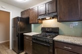 Located at 1275 Cunningham Rd SW in Marietta, Georgia, this single-floor residence offers a well-organized layout designed for comfortable everyday living. The spacious living area serves as the centerpiece of the home, featuring plush wall-to-wall carpeting, a ceiling fan with light fixture, and a striking dark wood-paneled fireplace that anchors the room with warmth and character. Large windows fitted with blinds allow natural light to fill the space while maintaining privacy.

The kitchen is equipped with dark espresso cabinetry, granite countertops, black appliances including a gas range and refrigerator, and a light-toned subway tile backsplash, all complemented by wood-look flooring that adds a clean, modern contrast.

The bedrooms are generously sized, each featuring soft carpeting and ceiling fans. The primary bedroom includes an en-suite bathroom with a vanity and mirror, as well as a dedicated walk-in closet. Additional bedrooms are served by their own closet space and convenient access to full bathrooms, each outfitted with a tiled tub and shower combination and chrome fixtures.

Throughout the home, neutral gray wall tones create a cohesive and versatile aesthetic, making it easy to personalize. The single-level floor plan ensures seamless flow between all living areas, offering both functionality and ease of access.