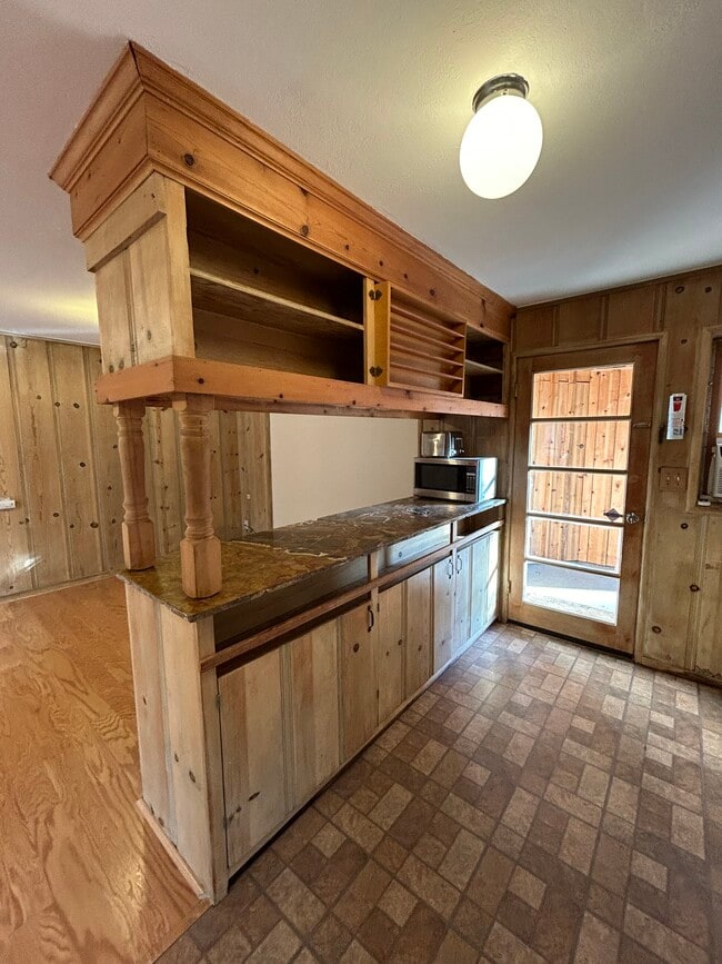 Kitchen island with cupboards, shelves, marble countertop, microwave, and toaster. - 1632 Live Oak Way