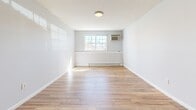 Located at 134 College Hwy in Southampton, Massachusetts, Unit F1 is a thoughtfully designed single-floor residence that makes efficient use of its space. The unit features warm hardwood-style flooring that runs consistently throughout, contributing to a cohesive and inviting atmosphere.

The kitchen is equipped with grey shaker-style cabinetry, a white subway tile backsplash, a stainless steel refrigerator, and a window above the sink that brings in natural light. A peninsula divides the kitchen from the adjoining living area, creating a practical open-concept flow.

The living and sleeping areas feature light grey walls, baseboard heating, and windows that allow ample natural light to fill the rooms. One bedroom features a distinctive grid-pattern accent wall, adding a subtle design detail, while another includes a reach-in closet with built-in shelving. A dedicated utility closet with an electrical panel provides additional storage and functionality. Wall-mounted air conditioning units are present in the living spaces for year-round comfort.

The bathroom is finished with large-format marble-look wall tiles surrounding the shower/tub combination, a grey vanity with a marble-top sink, wood-look tile flooring, and brushed nickel fixtures, lending the space a clean and modern aesthetic throughout.